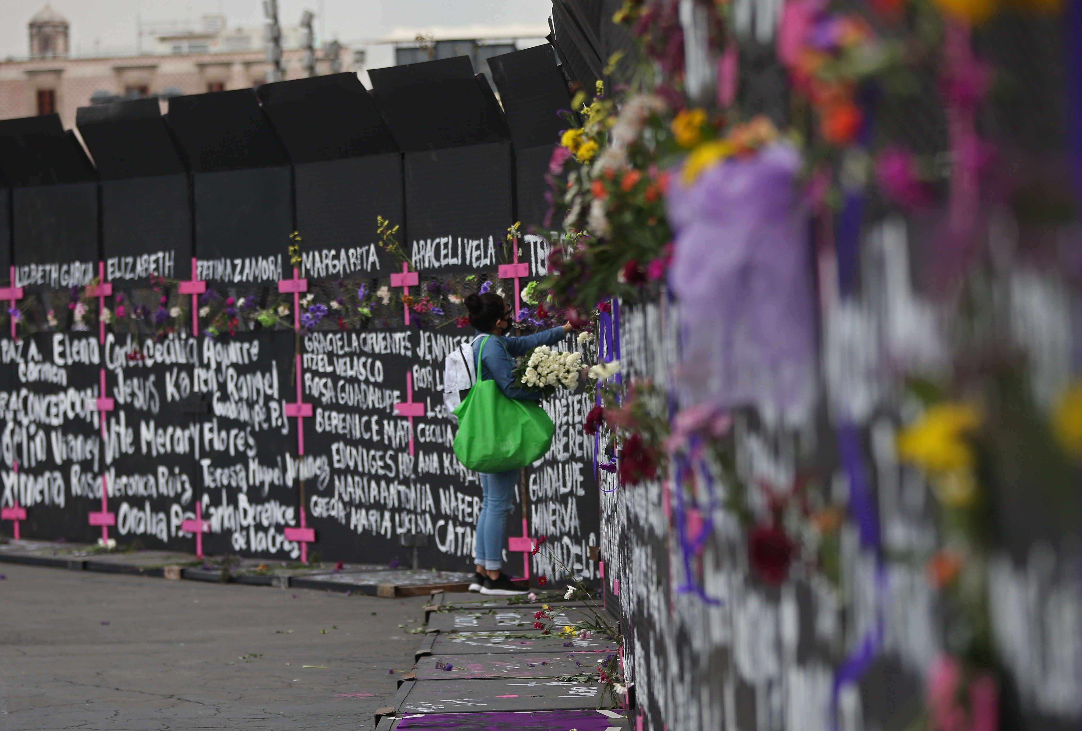 Una mujer coloca flores y carteles con nombres de víctimas por feminicidios en cercos metálicos instalados por el gobierno capitalino en una protesta contra los feminicidios el 7 de marzo de 2021, en Ciudad de México (México). El hartazgo por parte de los