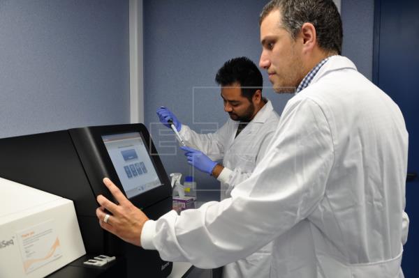 Los investigadores Iñaki Comas (Instituto de Biomedicina de Valencia IBV-CSIC) e Irving Cancino-Muñoz (Fisabio e IBV-CSIC) junto al secuenciador. Imagen facilitada por Fisabio.