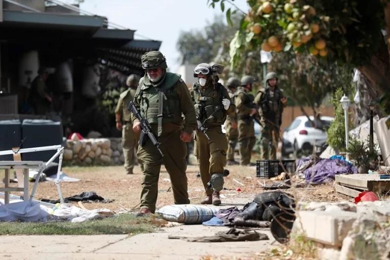 Soldados israelíes caminan junto a un cadáver en el kibutz de Kfar Aza, junto a la frontera con Gaza. EFE/EPA/Atef Safadi